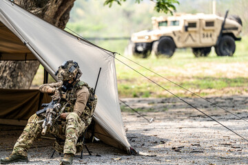 Special forces soldiers preparing tactical gear at military field base camp with weapons and...
