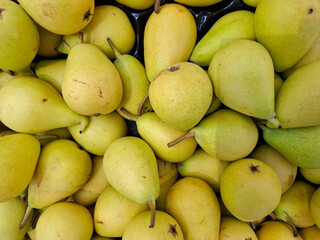 Ripe yellow pears on display at a vibrant farmers market in Spain during the harvest season