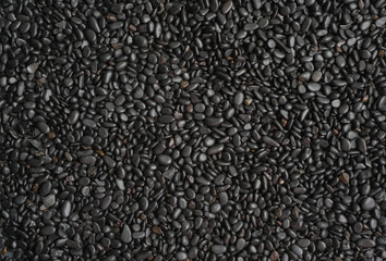 Black Pebble background. Beautiful creative natural background with visible little pebbles texture and rough uniform structure. Pebbles on the ground. Rough texture, construction material background
