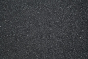 Black sand background. Beautiful creative natural background with visible little sand texture. Sand on the ground. Rough texture, construction material background