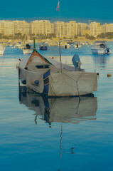 Traditional Fishing Boat Anchored in a Maltese Harbor at Sunset,A traditional covered fishing boat...