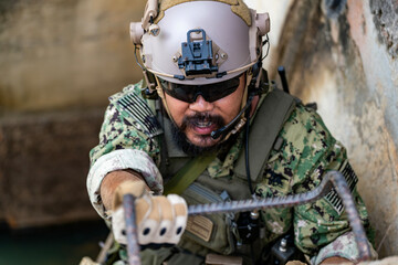 Close-up of special forces soldier climbing rope ladder during urban operation, wearing tactical...