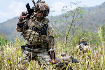 Special forces soldier holding rifle and communicating on radio during tactical operation in...