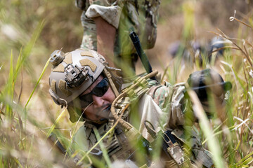 Special forces soldier holding rifle and communicating on radio during tactical operation in...