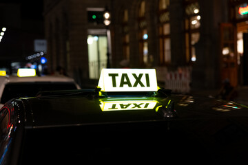 Illuminated taxi sign on car roof with night city street reflections. Urban transportation and city service concept
