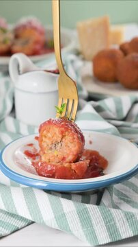 Fork cutting through Sicilian arancini with tomato sauce. Juicy texture, rich filling, and crispy crust. Authentic Italian street food moment. High quality FullHD footage