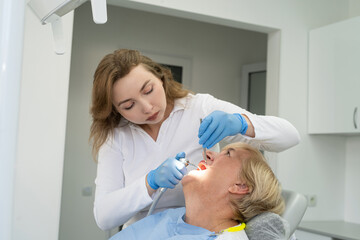 Senior female client having repairing tooth at dentist's office. Concept of ready for teeth cure