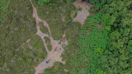 Aerial view of mountain bike cyclists travelling along sandstone pathway in forest landscape. Wirral, Merseyside, UK.