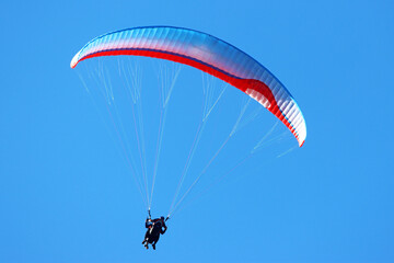 Tandem Paraglider flying in a blue sky	