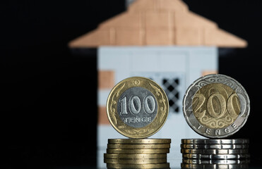 Coins stacked in a column with the dynamics of savings growth against the background of a house....