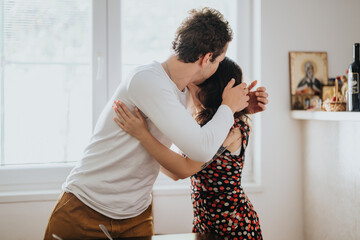 A young couple shares a loving embrace in a sunlit room, conveying warmth and affection. The home...