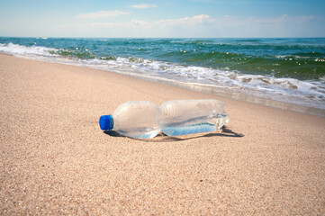 Empty plastic bottle on a sand beach. Garbage on a seashore