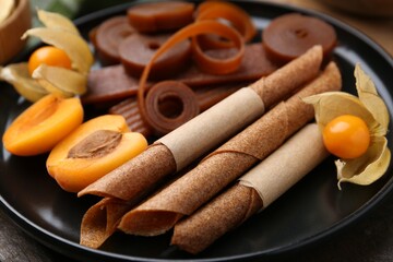 Tasty fruit leather, physalis and apricots on wooden table, closeup