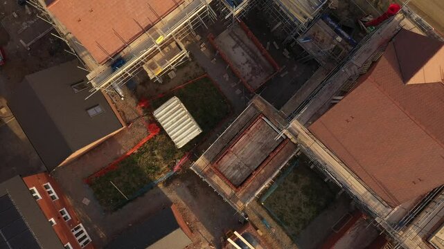 Top-down aerial view of residential construction site with scaffolding and partially built houses