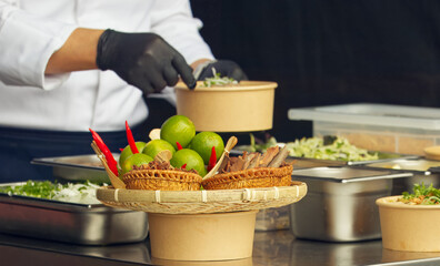 A chef wearing black gloves prepares a dish during a cooking demonstration at a farmers market,...