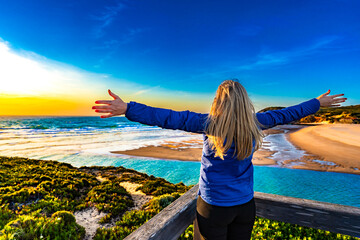 Beautiful middle aged woman standing with outstretched arms at viewpoint on picturesque Amoreira...