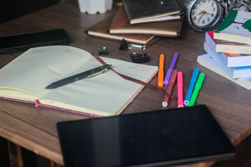 For educational purposes, several colored markers and notebooks are on the wooden table.