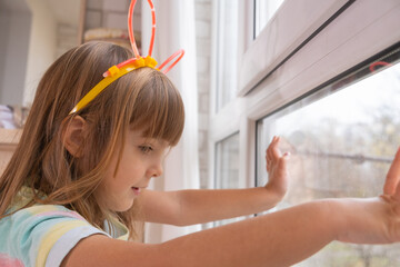 Young girl with colorful headband gazes out the window