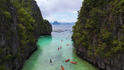 Aereal view of Crowds Kayaking between cliffs and Swimming in the Shallow Waters of Big Lagoon, Minoloc Island, El Nido, Palawan, Philippines