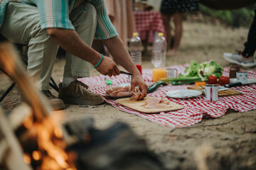 A person slices ingredients on a checkered blanket surface during an outdoor camping trip. Fresh...