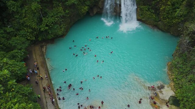 Aerial Drone Shot of Kawasan Falls with Tourists Swimming in Crystal Clear Blue Water Amidst a Jungle Oasis in Cebu, Philippines