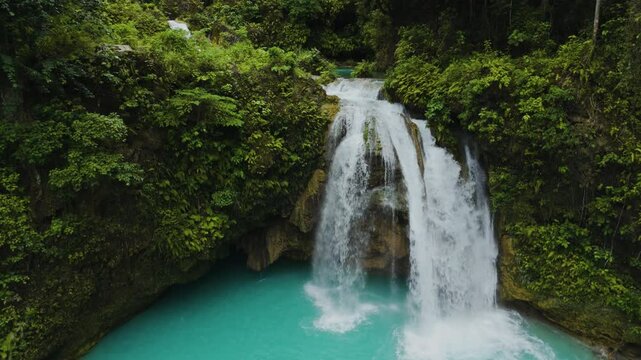 Slow mo Close-Up of Twin Waterfalls at Kawasan Falls Pouring into a Turquoise Pool Surrounded by Mossy Cliffs and Tropical Greenery. Cebu, Philippines.