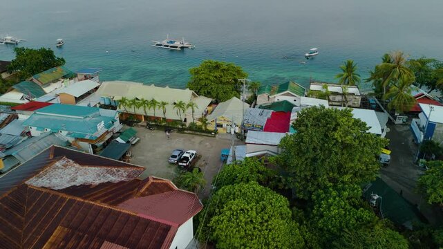 Aerial View of Tropical Waterfront and Vibrant Turquoise Waters Beachfront with bangkas in Moalboal Sardine Run, Cebu, Philippines