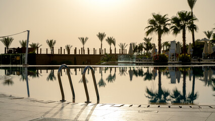 Swimming pool by the sea at sunrise