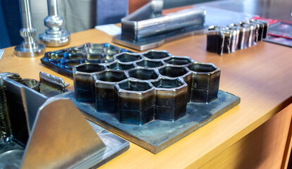 Objects printed on 3D printer from filament of molten metal on table. Object printed by 3D printer from metal. Additive manufacturing solution. Object created on 3D printer from melting metal thread