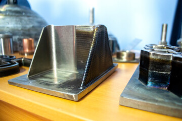 Objects printed on 3D printer from filament of molten metal on table. Object printed by 3D printer from metal. Additive manufacturing solution. Object created on 3D printer from melting metal thread