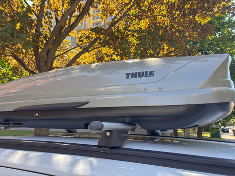 Bratislava, Slovakia, Europe - Jun 22, 2025: Title: silver Thule roof box mounted on a white car, parked on a city street on an autumn day, cargo carrier for a trip, concept of travel, transportation