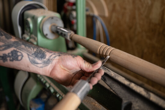 Carpenter using wood lathe to create wooden furniture leg