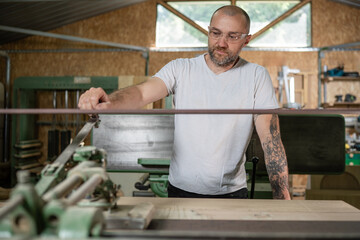 Carpenter using belt sander in workshop: processing wood plank