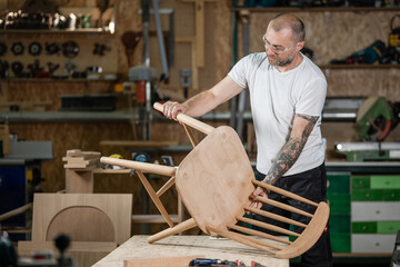 Carpenter assembling wooden chair in workshop