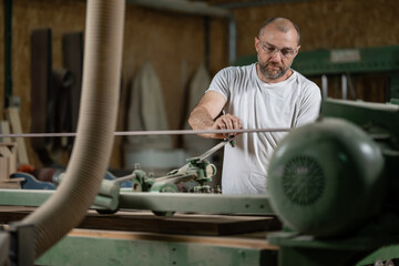 Carpenter working wood with belt sander in workshop