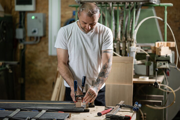 Carpenter using clamps gluing wood in workshop