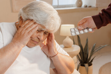 Senior Woman With Headache Receiving Pills for Migraine Pain Relief and Home Healthcare Concept