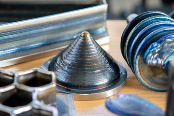 Objects printed on 3D printer from filament of molten metal on table. Object printed by 3D printer from metal. Additive manufacturing solution. Object created on 3D printer from melting metal thread