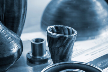 Objects printed on 3D printer from filament of molten metal on table. Object printed by 3D printer from metal. Additive manufacturing solution. Object created on 3D printer from melting metal thread