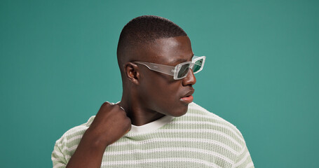 Black man, fashion and sunglasses with cool, style and confidence on green studio background. Gen...