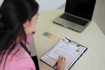 A young asian female Head of HR is reading resume and making a call for the recruitment interview ...