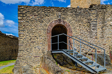old stone wall with arched entrance and metal stairs 