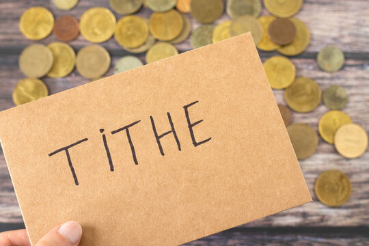Hand holding an envelope with tithe on top of coin money. Blessing by God Jesus Christ, offering and giving, Christian biblical concept.