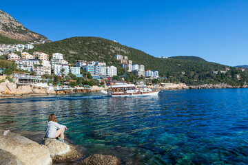 Woman looking at sea and historical town Kash placed on hills by coast of mediterranean sea in...