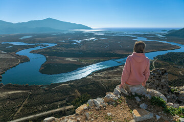 Woman looking from acropolis on top of mount of ancient Greek city Kaunos to Dalyan river, Sulungur...