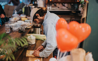 A chef diligently works in a cozy cafe kitchen, creating culinary delights surrounded by a warm...