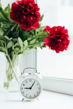 Vintage clock and vibrant peonies in serene setting