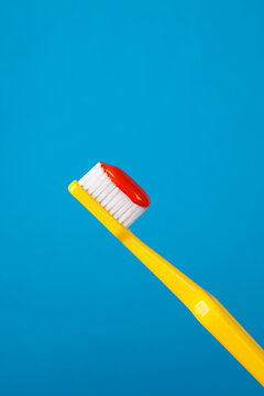 Yellow plastic toothbrush with bright red toothpaste