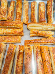 Freshly baked cheese straws with herbs and spices resting on metal tray