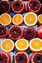 Rows of sliced ​​ripe pomegranates and juicy oranges displayed at a farmers market in Israel